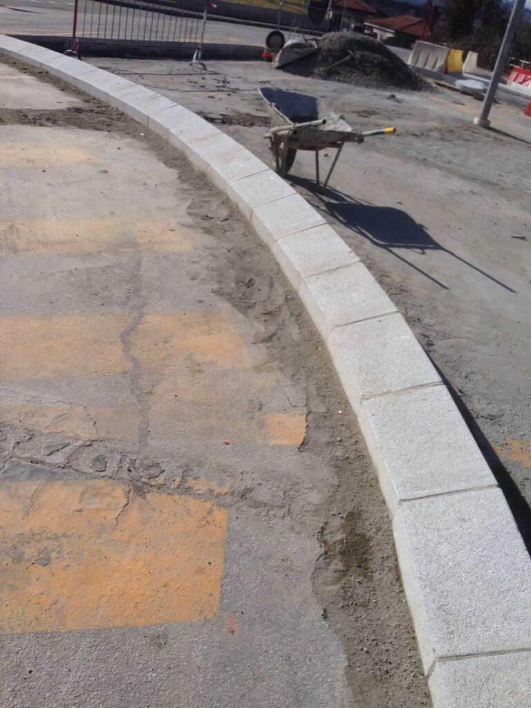 Cordoli in pietra naturale per marciapiede urbano in costruzione a Cuneo.