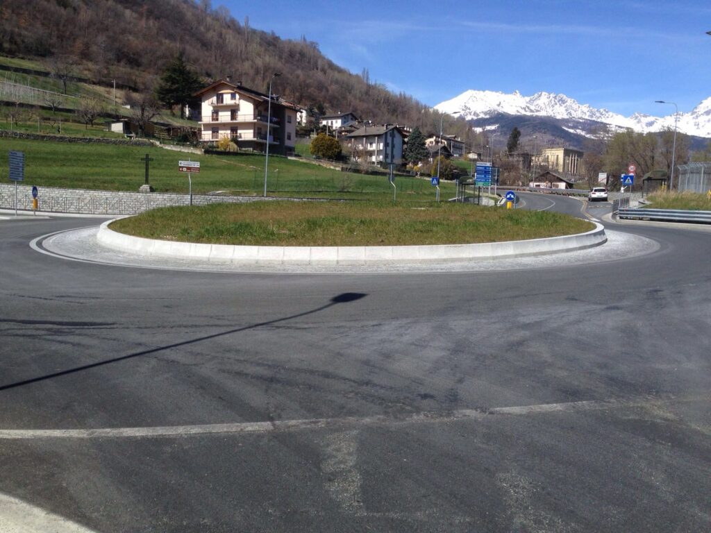 Rotonda stradale con cordoli in pietra naturale Cuneo e sfondo montano.